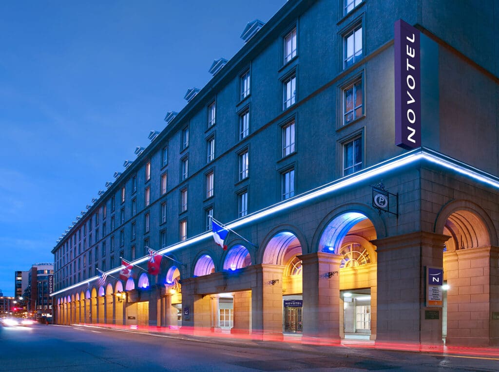 A photo of the font entrance and archways of the Novotel Toronto Centre Hotel at dusk in the early evening.
